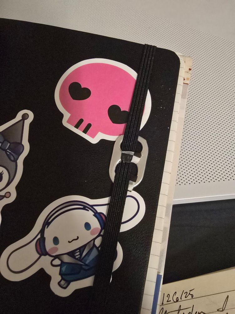 A soda tab attached to the elastic enclosure of a journal.