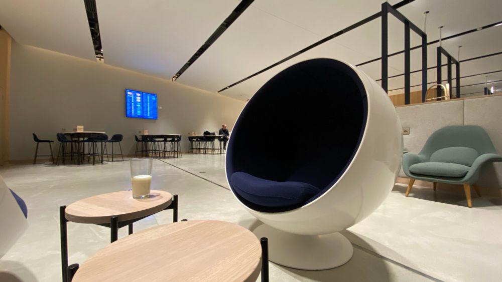Finnair lounge at Helsinki Airport. White walls & ceiling in a wide angle shot. There is one of those 60s egg chairs and half a glass of milk on a table. It’s a strange mix of the Korova Milk Bar & the room at the end of 2001. 