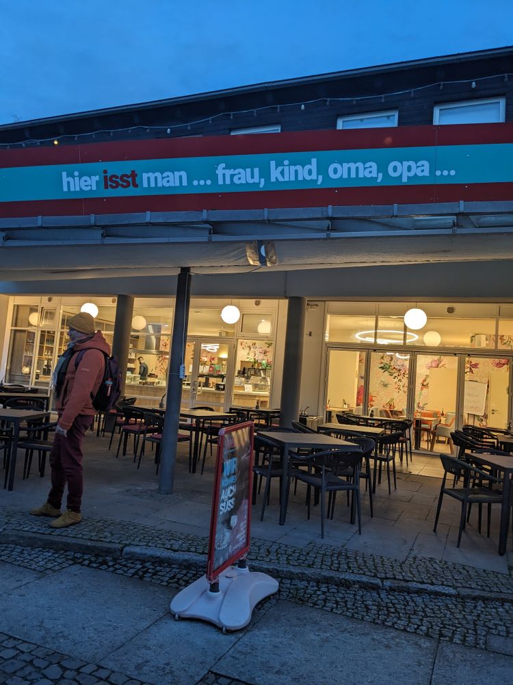 Restaurant von außen mit Beschriftung "hier isst man... Frau, Kind, Oma, Opa... "