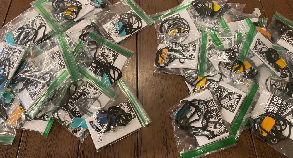 A brown table with two piles of whistle kits. English on the left, Spanish on the right. 