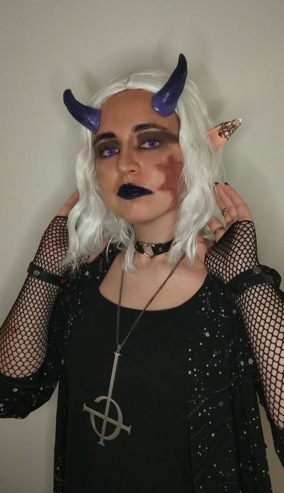 nameless ghoul OC cosplay with white hair, pinty ears, purple horns and big red scar on the right side of the face. they are wearing black clothes and era 3 grucifix