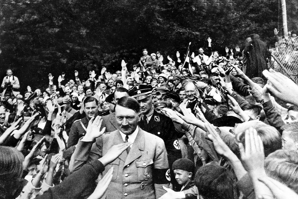 A crowd of people saluting Adolf Hitler.