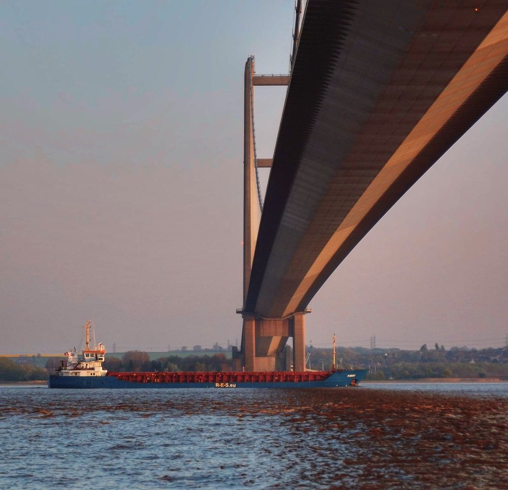 A ship on the Humber Estuary passes underneath the Humber Bridge heading for Goole. 