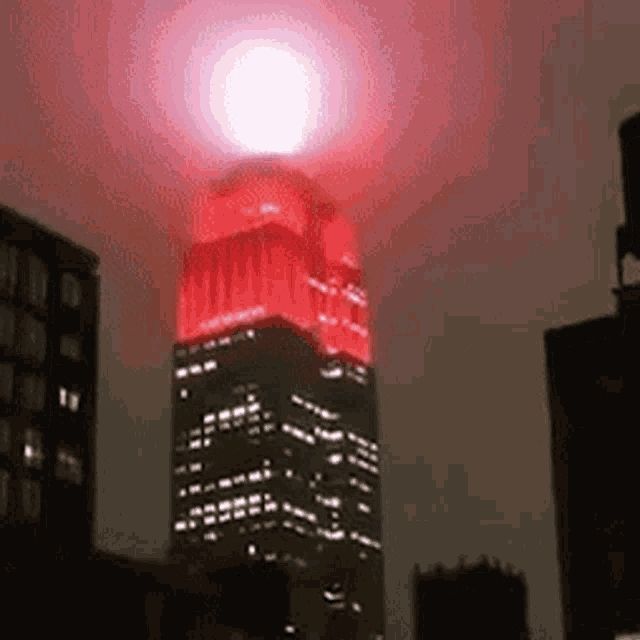 Auf einem Hochhaus leuchtet ein grellen pinkes Licht in den Nachthimmel 