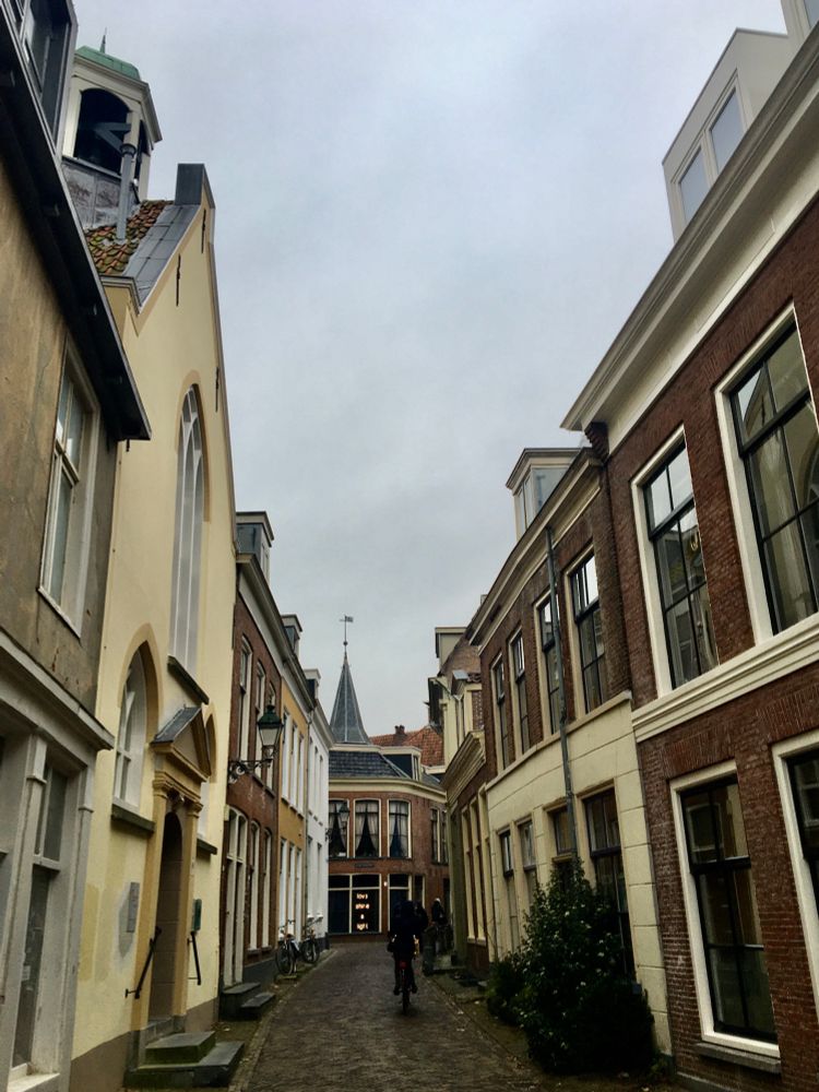 Lopend door de smalle Grote Kerkstraat, met links het oude Waalse kerkje, zie je in de verte de tekst: love shine a light. 
Het is nogal donker. De letters (lampjes) lichten op vanachter een raam.