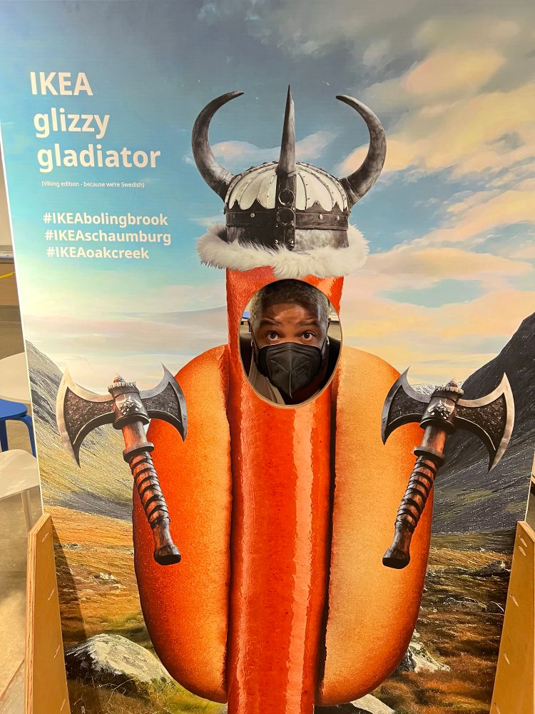 Me wearing a black n95 respirator, in a head-cut-out photo op station with a Nordic themed hotdog 