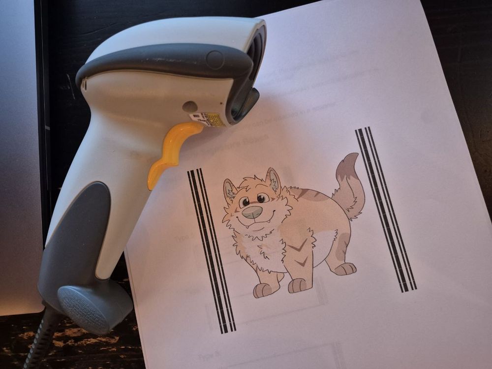 A Zebra barcode scanner laying atop a sheet of paper with a picture of crumb surrounded by oddly tall barcodes printed on it.