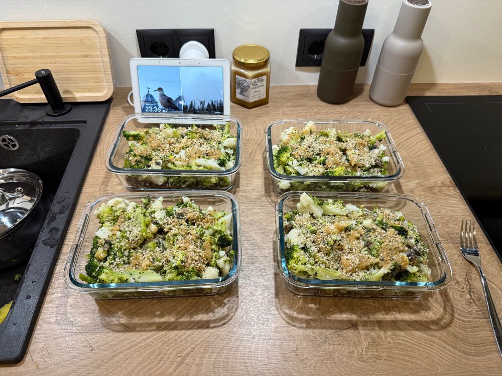 Four glass bowls filled with a mixture of vegetables, sauce and seeds, sitting on top of the counter.