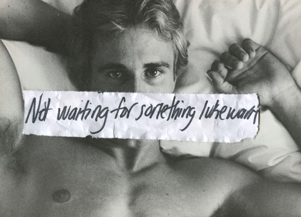 Vintage, shirtless male resting on a pillow with the words "Not waiting for something lukewarm" written across his mouth.