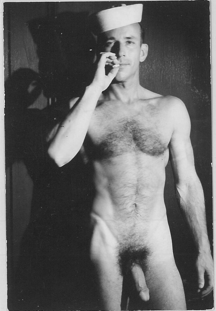 Steve Marl smokes a cigarette in high contrast film noir style black and white while wearing nothing but his sailor hat.