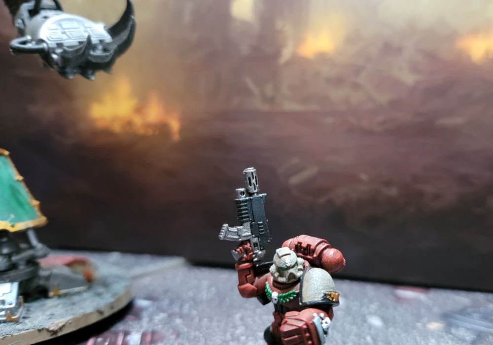 A Space Marine sergeant, with a giant murderbot lurking in the background. 