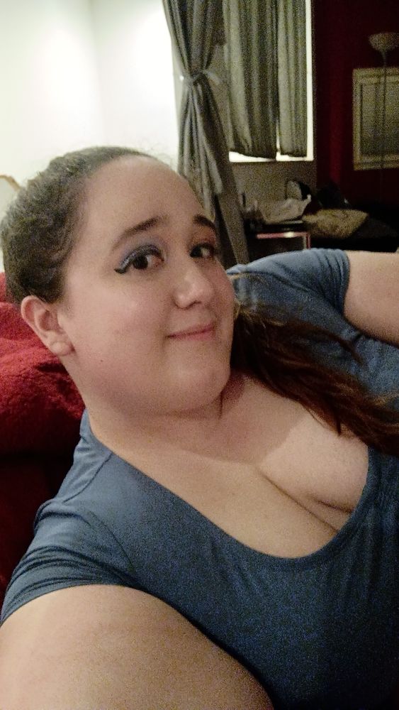 A woman wearing a low cut shirt smiles at the camera 