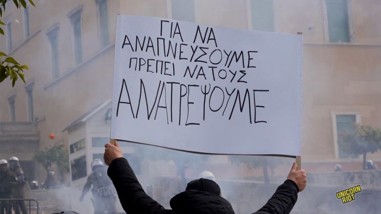 
Protester holds up a sign reading “to breathe, we have to overthrow them,” outside the Greek Parliament during the general strike on Feb. 28, 2025
