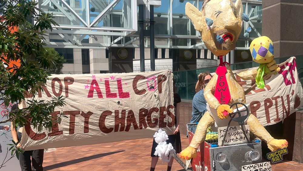 banner in front of courthouse: "drop all cop city charges" + paper mache wearing "fowler" tie and other messages spoofing charges