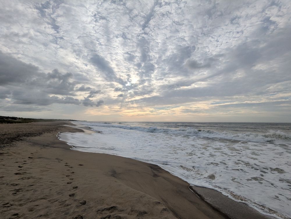 A beach w/ the morning sun trying to poke through the clouds