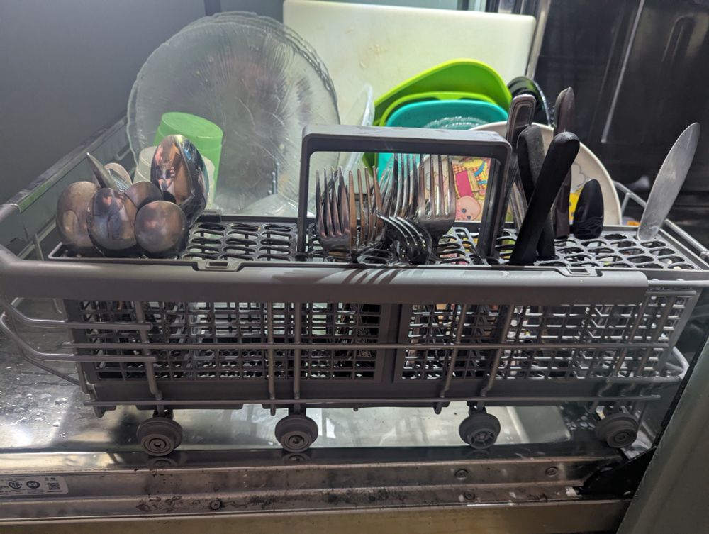 Silverware correctly loaded in a dishwasher. Spoons up. Forks up. KNIVES DOWN!