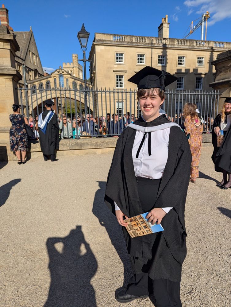 Eli in gown and hood after ceremony. Bridge of sighs in the background. 