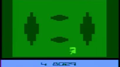 A screenshot from the Atari 2600 game “E.T.”, the title character in a green field with some pits showing on the screen above him.