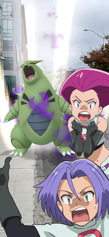 An AR picture of the pokemon Tyranitar, with the Team Rocket members Jesse and James screaming in fear nearby.