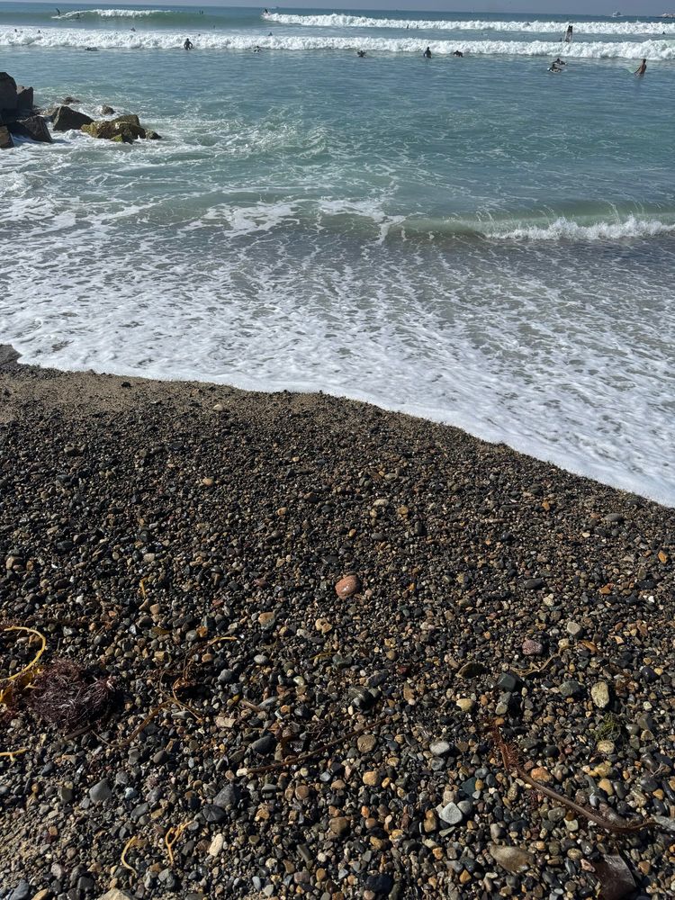 Picture of a pebble and sand beach as the waves come in.