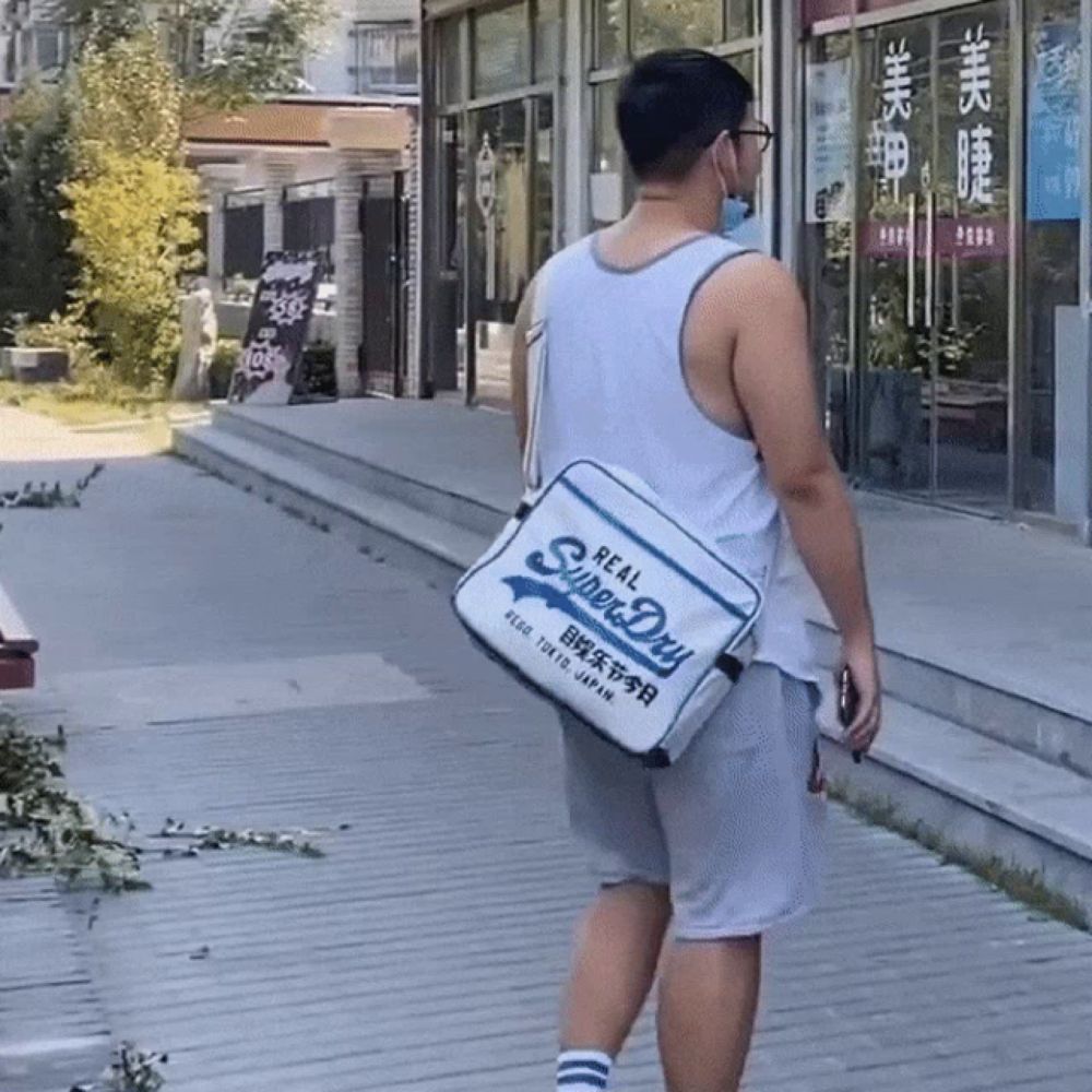 a man walking down a sidewalk with a bag that says real super dry on it