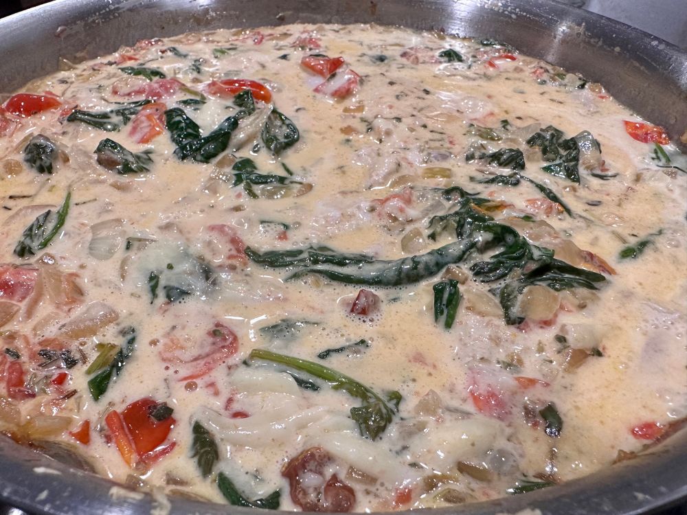 An image of Tuscan pork chops simmering in a pan