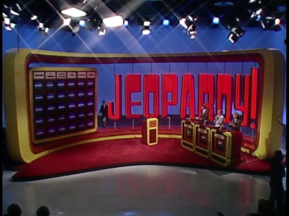 Jeopardy! logo from 1984, showing capital letters and an exclamation point whose line is the same height as the letters, but which is raised to fit the dot underneath it.