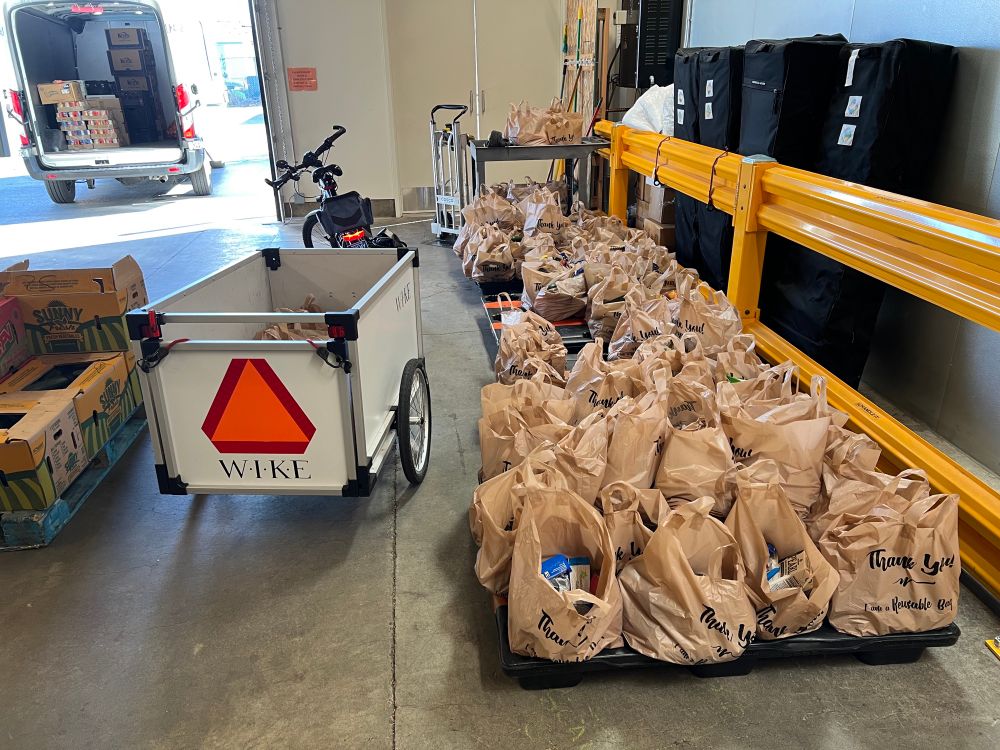 Bike and trailer in food bank warehouse next to many bags of groceries