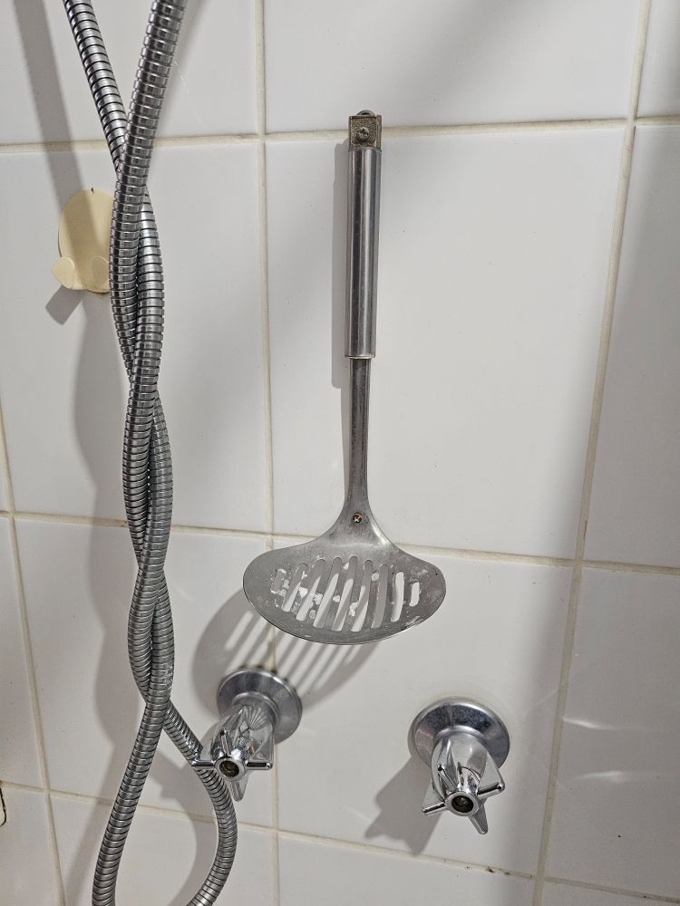 A ladle screwed to a bathroom wall