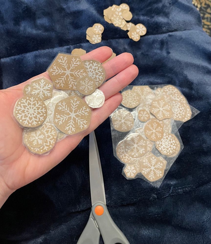 A handful of brown paper circles printed with snow flakes, laminated in packing tape