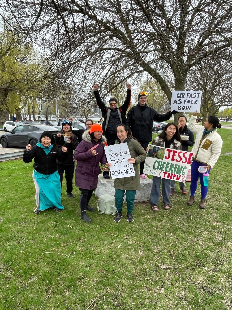 Group of 10 friend holding up signs and cheering at a marathon