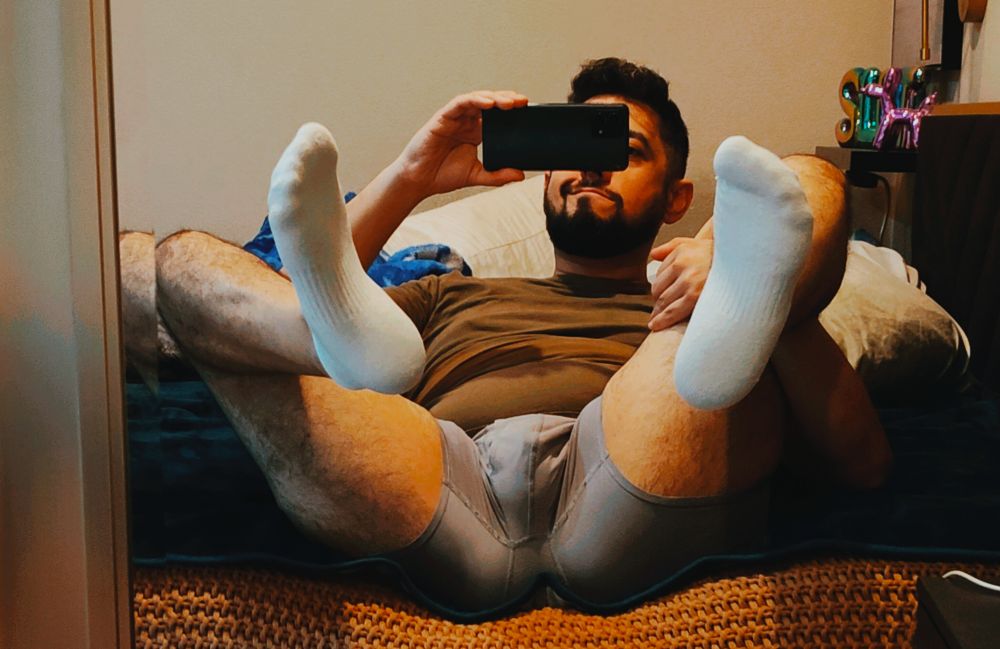 Picture of me in my underwear and a t-shirt showing socks on my bed taking a picture in the mirror