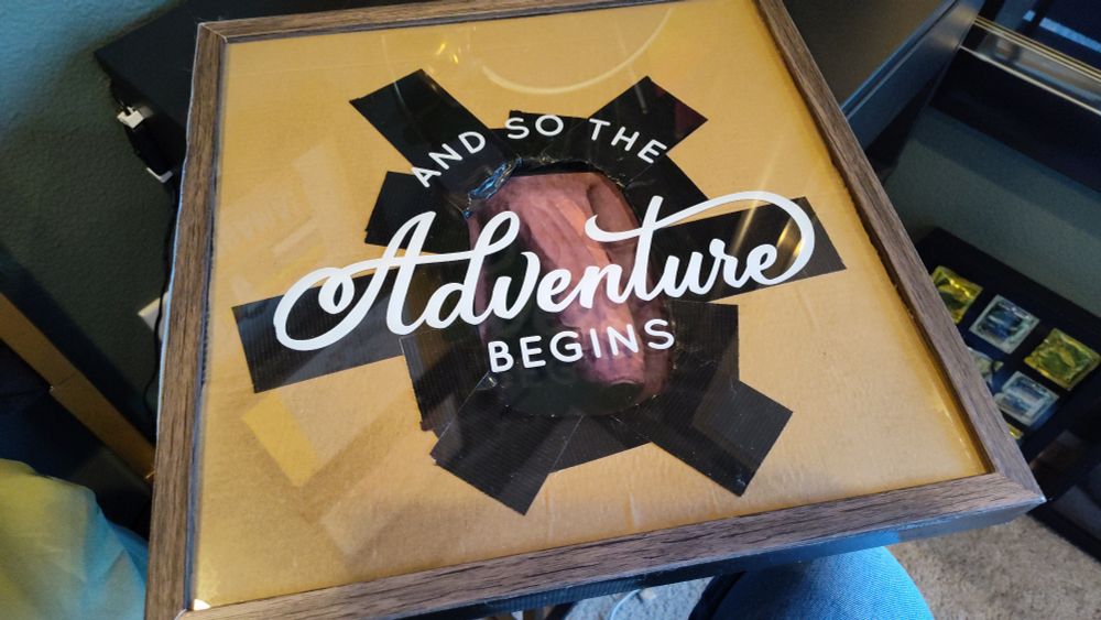 A picture that I made from a Goodwill find and says and so the adventure begins and it looks like a glory hole with it a guy's cock sticking through the front