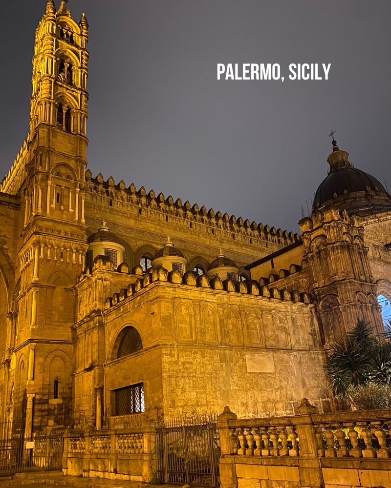 Palermo cathedral glows at night against a gray sky