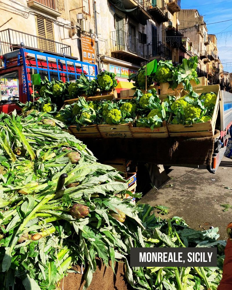 Cauliflower and artichokes spill out of a cart into the street in Monreale, Sicily