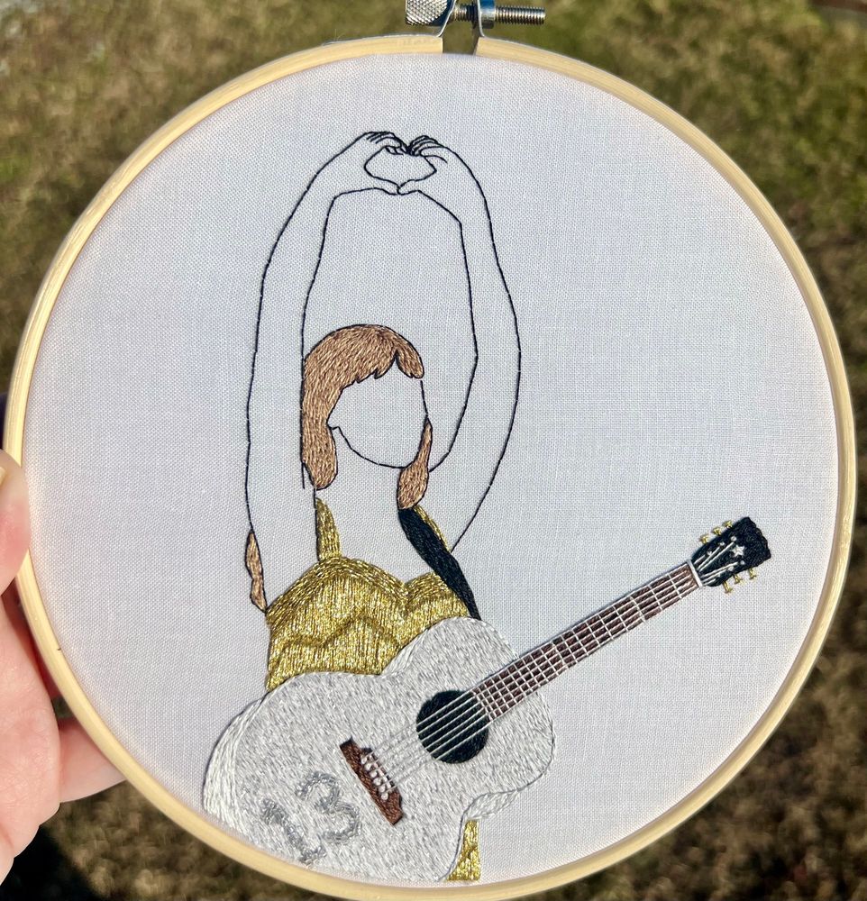 Hand embroidered hoop art of taylor swift during the fearless era doing a hand heart