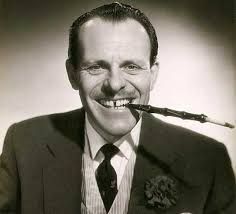 Terry Thomas with a large cigarette holder looking like the ultimate cad 