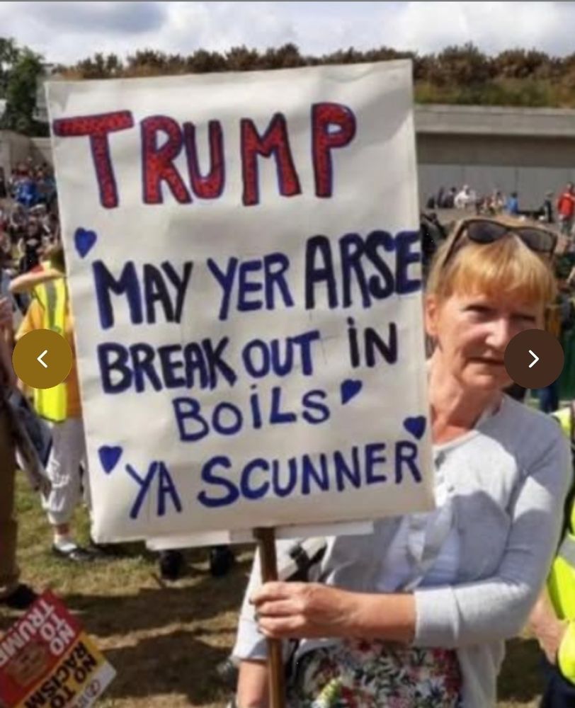 A woman in Scotland holding a sign that reads: TRUMP May yer arsenal break out in boils ya scunner.