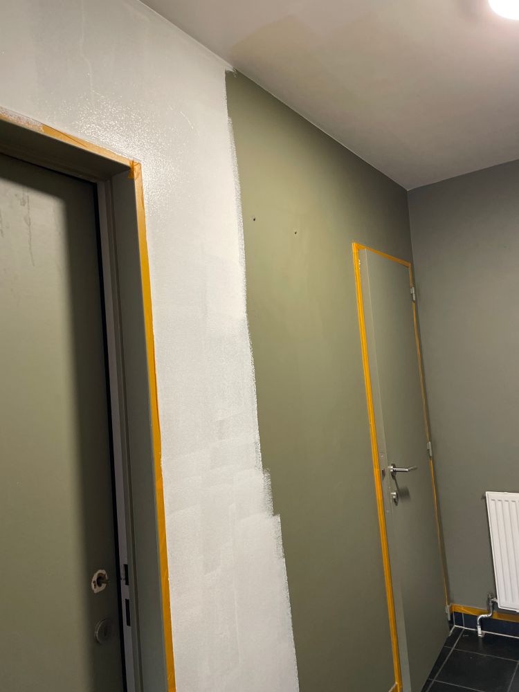 hallway with two doors. the walls and doors are army green, half of it is already painted white