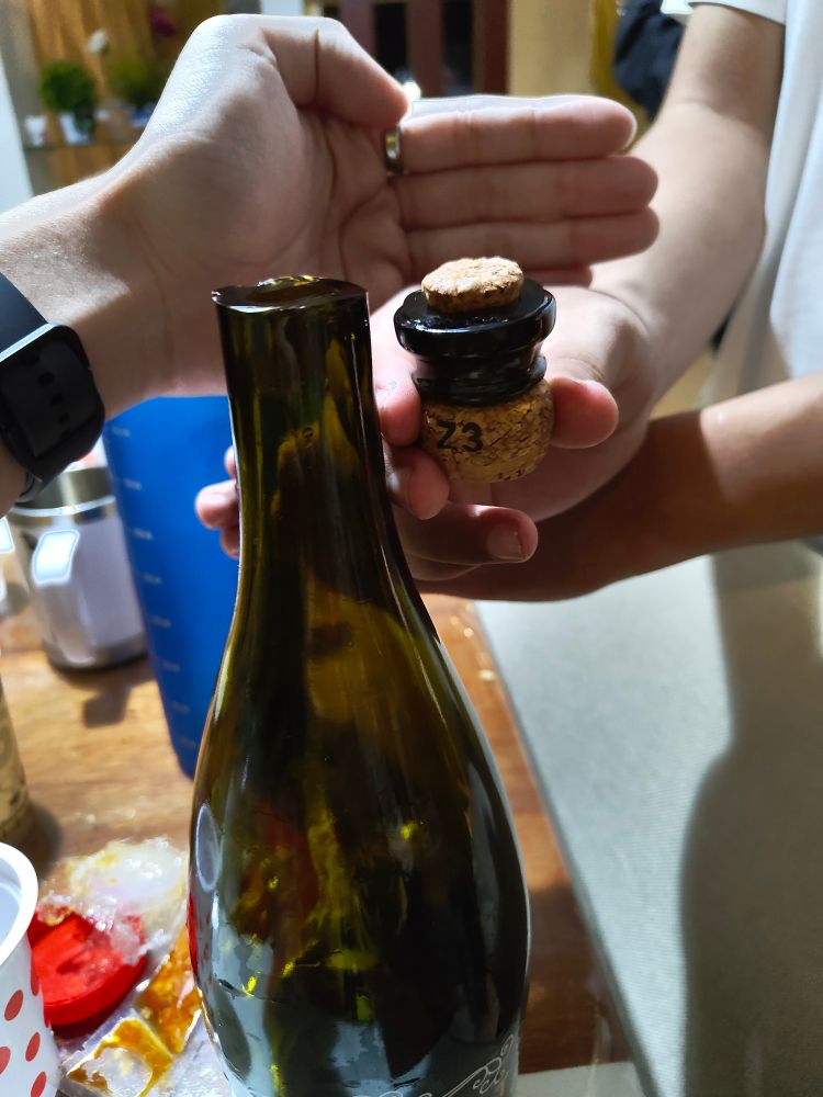 A bottle of sparkling wine that has been very well sabered where the top is placed to the side of the neck where the cut has happened.