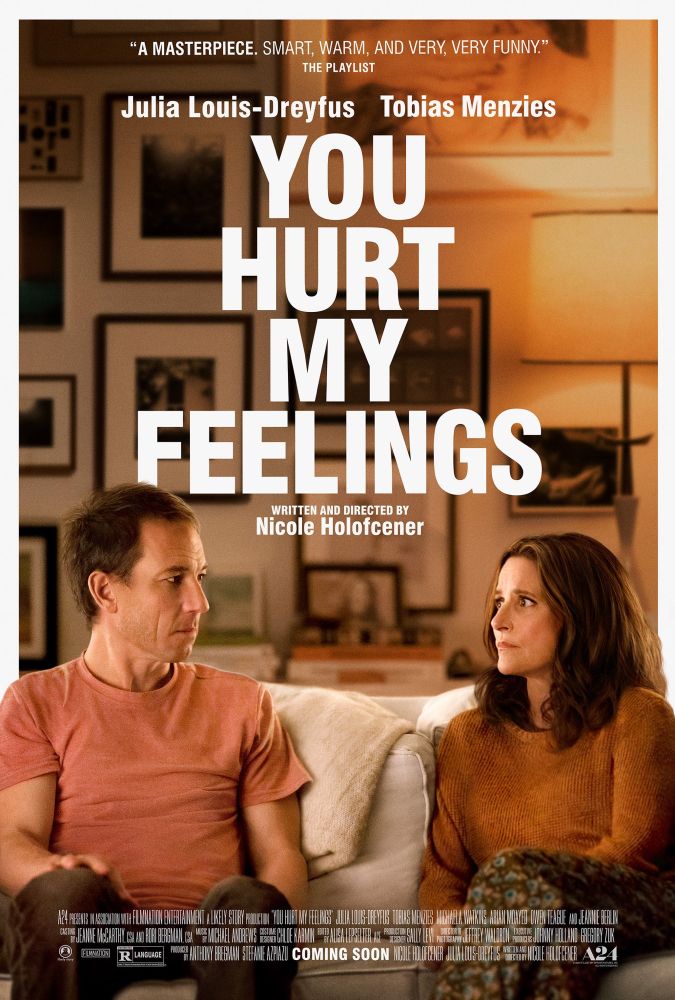 Movie poster for “You hurt my feelings”. The poster shows two middle-aged people (actors Julia Louis-Dreyfus and Tobias Menzies) sitting next to each other in an off-white couch, looking at each other with slight worry and confusion. They appear to be sitting in a nicely designed living room, taking up the lower half of the poster. The title fills most of the upper half with big white letters, but at the very top is a quote from The Playlist: “A masterpiece. Smart, warm, and very, very funny.” Below the title it says “written and directed by Nicole Holofcener”