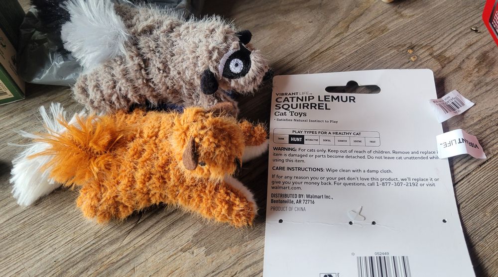 A fuzzy gray stuffed lemur and a fuzzy brown stuffed squirrel next to a card saying Catnip Lemur Squirrel Cat Toys. Both lemur and squirrel are tiny 
