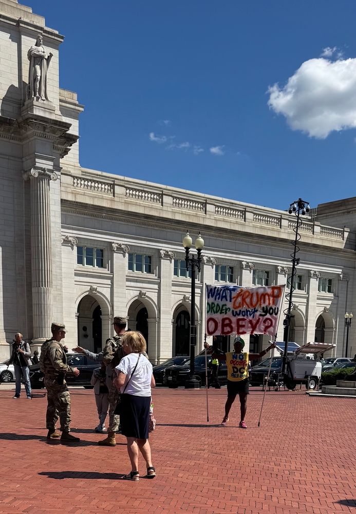 Activist holds sign near National Guard at Union Station DC