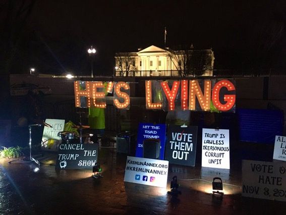 Activists hold sign HE’S LYING 
