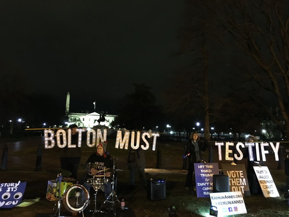 Activists hold sign BOLTON MUST TESTIFY 
