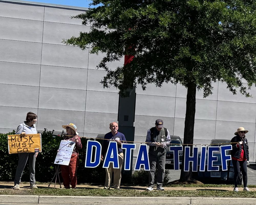 Activists hold sign DATA THIEF at Tesla 