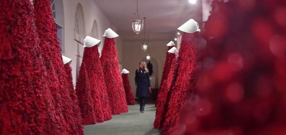 Melania in hall of red Christmas trees wearing handmaidens tale hats