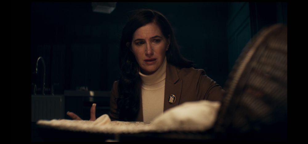 Kathryn Hahn as Agatha Harkness, approaching a woven bassinet. Her expression is of worry and a tear runs on her cheek.