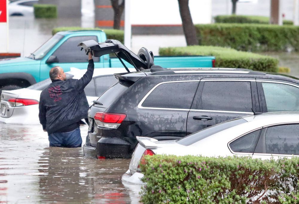 A man in waist-high water tries to access his vehicle.