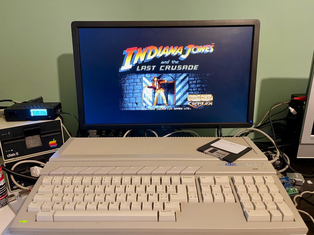 An Atari STE turned on and showing the title screen of the game Indiana Jones and the Last Crusade from 1989.